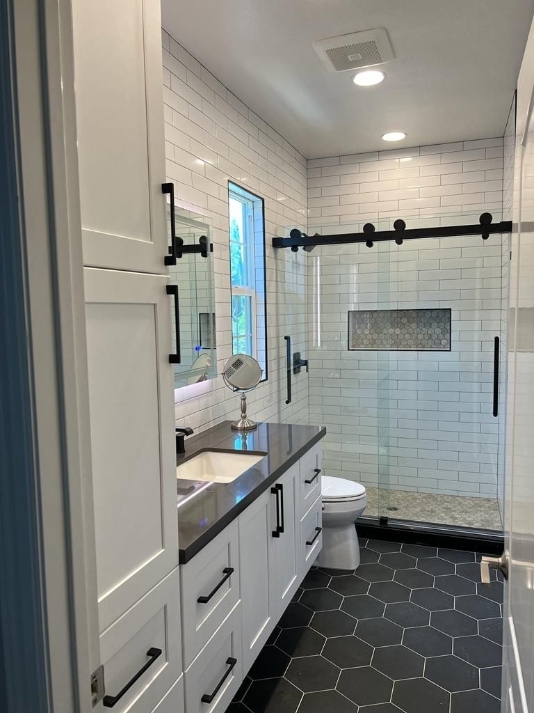 Frameless glass walk-in shower with subway tile and hex stone floor